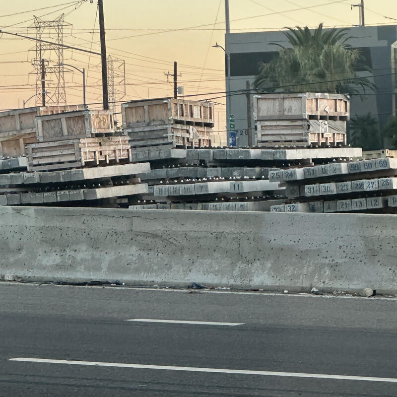 Stacked concrete barriers and crates along an urban freeway